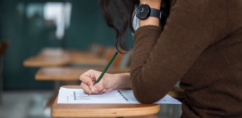 woman sitting at school desk taking college admission checklist