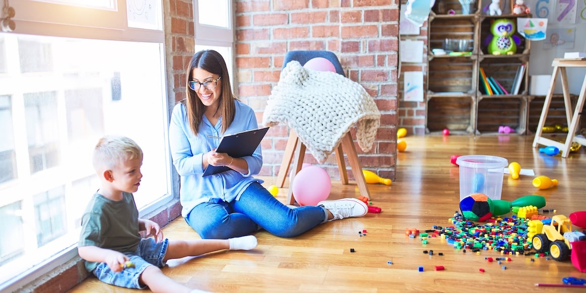 Social worker sitting on the floor with child patient using evidence-based practice